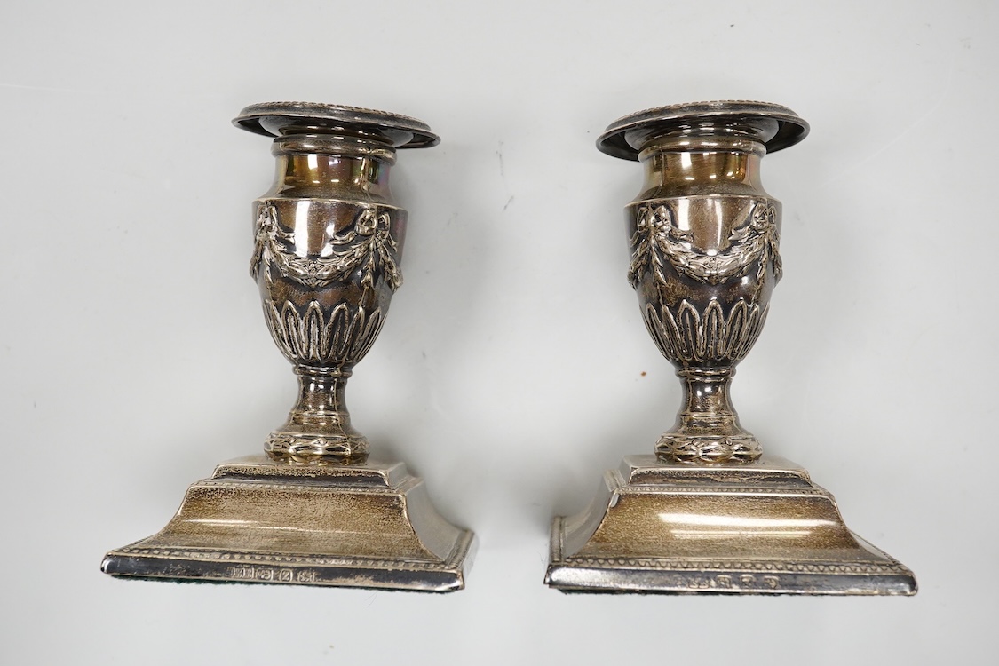 A pair of late Victorian silver mounted dwarf candlesticks, embossed with swags, on beaded bases, by Barker Brothers, Birmingham, 1899, height 11.5cm, weighted.